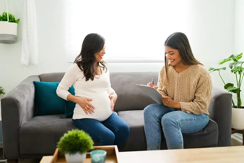Pregnant surrogate smiling during a warm consultation with a surrogacy professional.