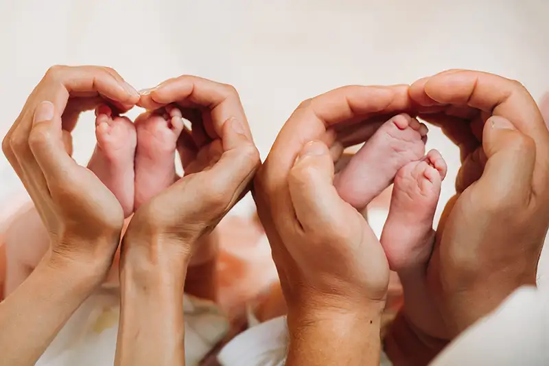 Adult hands holding a newborn baby’s feet.